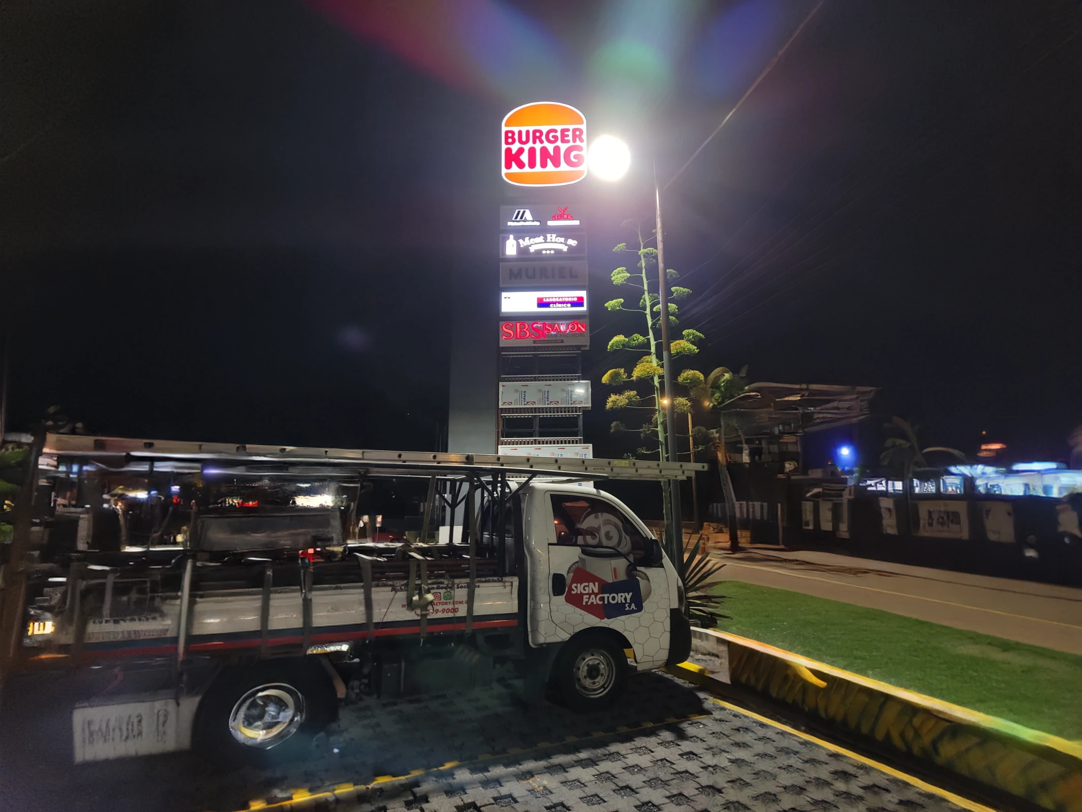 Tótem iluminado con logos de Burger King, Meat House, Muriel, un laboratorio clínico, SBS Salón.