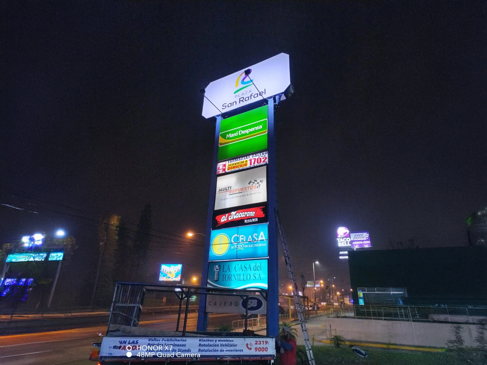 Tótem de Plaza San Rafael iluminado con logos de Maxi Despensa, Farmacias Galeno, Multi repuestos, Al macarone, Celasa y La Casa del Tornillo.