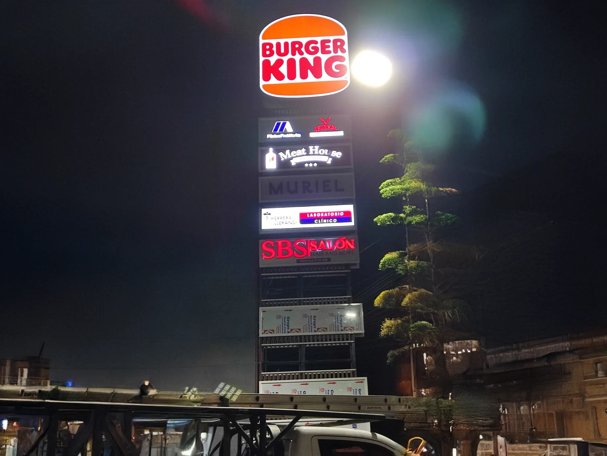 Tótem iluminado con logos de Burger King, Meat House, Muriel, un laboratorio clínico, SBS Salón.