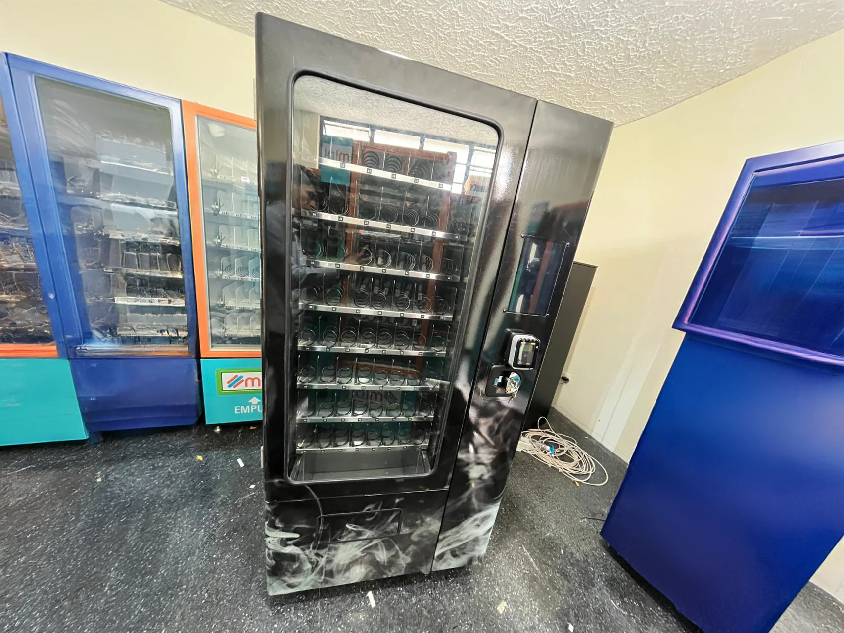 Máquina dispensadora de vapes negra con diseño de humo