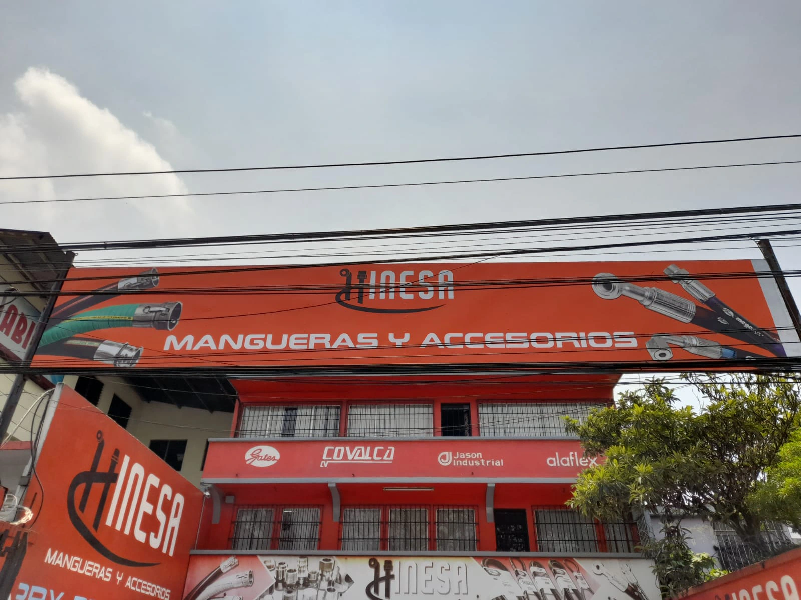 Fachada y cenefa naranja para Hinesa con mangueras desde otra perspectiva