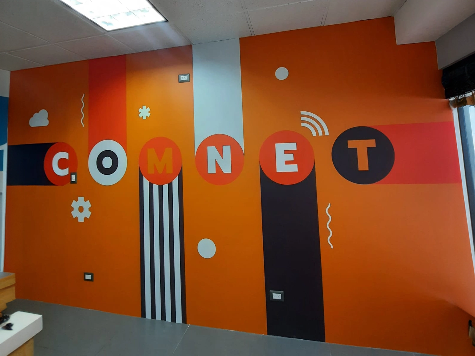 Mural anaranjado con garabatos blancos para COMNET